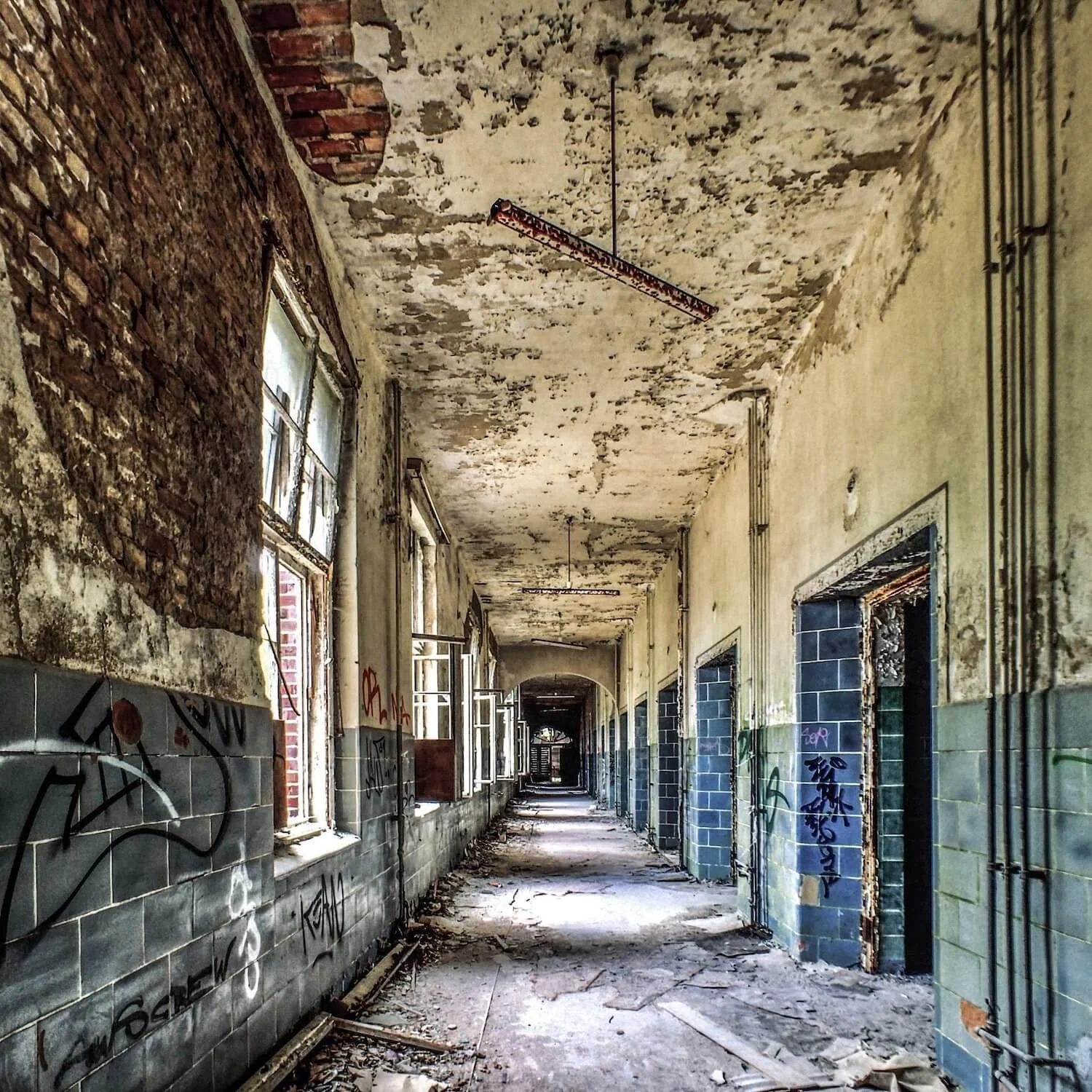 An endless decayed hallway with chipped mint-green paint at the abandoned Beelitz Heilstätten hospital